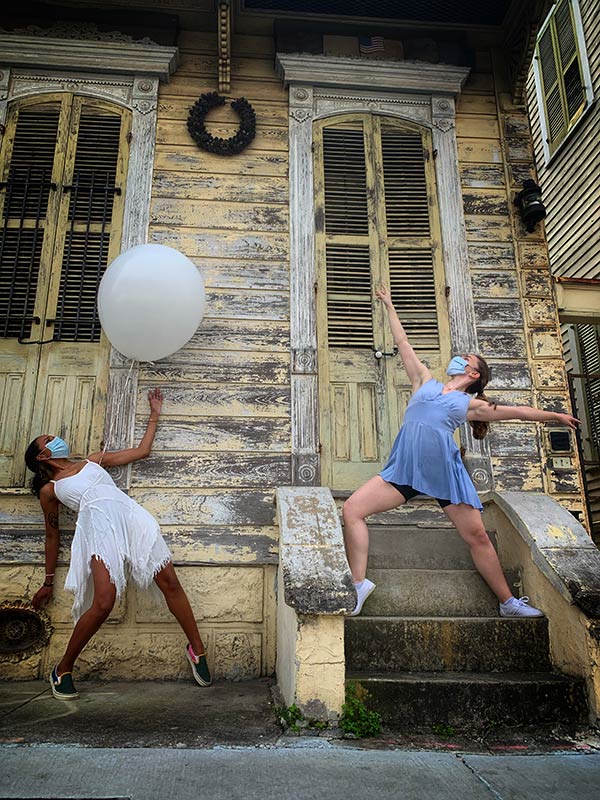 The Body Remembers. Two dancers with a balloon dancing in front of a yellow house. 